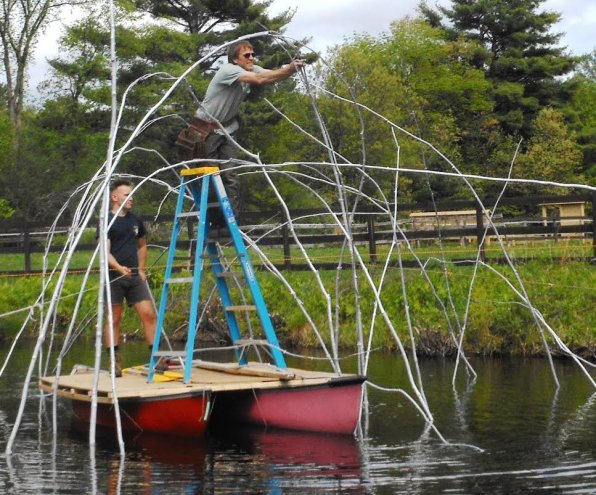 Being a sculptor sometimes means climbing on a ladder balanced perilously on top of two canoes in the middle of a body of water, as Andy Moerlein illustrates here.