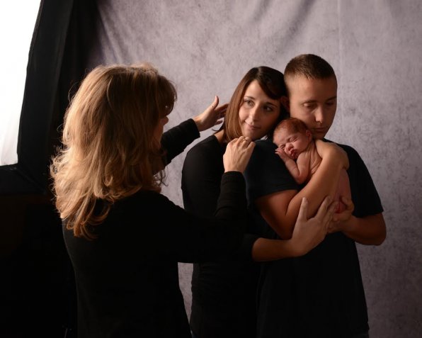 Photographer Nylora Bruleigh works with a young couple and their baby to set up a shot.