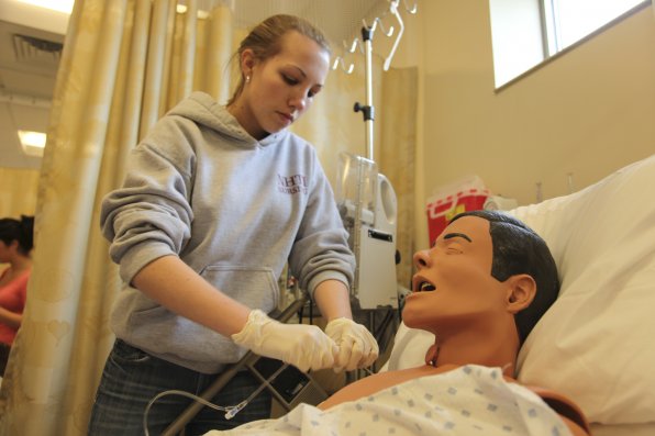 First year nursing student Kaylee Johnson hooks up an IV tube to her "patient," a training dummy. The mannequins can be programmed to display the symptoms of real-life ailments.
