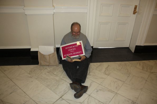 Mark Barker sits in a State House hallway where he has been holding a daily prayer vigil since the state budget proposal. He plans to continue the vigil “for the duration,” or until a budget that allows “help for the vulnerable” is passed. “Gandhi said ‘There is enough in this world for everyone’s need, but there is not enough in this world for everyone’s greed,” Barker said.