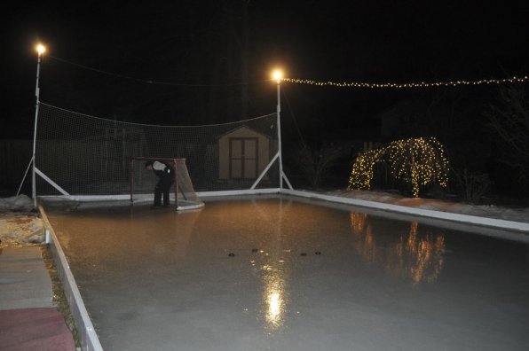 Pieter Hollenberg places a net at one end of the hockey rink he built in his backyard. Careful Pieter, it’s slippery out there!