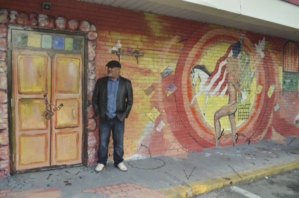 Saad Hindal stands in front of the mural he painted at the Concord Farm convenience store.