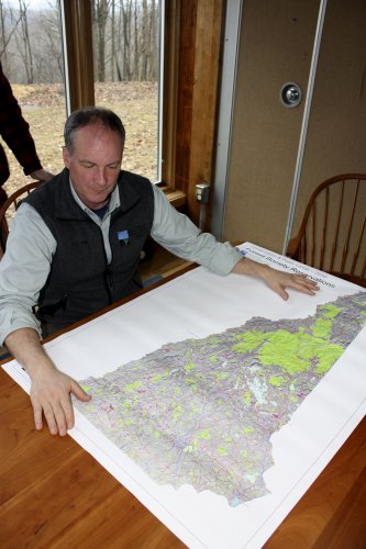 Jack Savage contemplates a map of the New Hampshire forestlands owned or managed by the society.