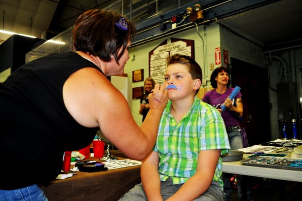 Just Lisa of Granite State Roller Derby paints a mustache on Ian Macaig, 11.