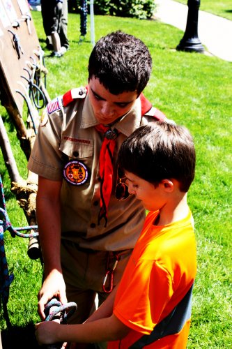 Star Scout Cory Yelle helps 7-year-old Cedric Myler with some knot techniques.