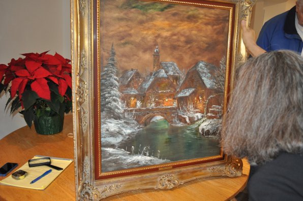 Below, Richardson examines a painting purchased by Bruce and Nancy Packard. Bruce was stationed in Germany while in the army, and several German artists used to display paintings at the barracks for soldiers to see. Because the artist is unknown, Richardson estimated it would sell for between $100 and $150 but encouraged the Packards to hang on to it.