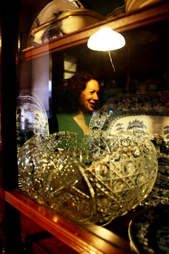 Woman's Club president Lisa Schermerhorn reflected in the glass of an antique china cabinet.