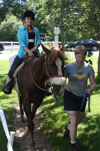 Camper Savannah Hawkins (led by Kelly Eaton) rides Cinnamon.
