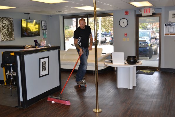 Buzz Ink owner Rick Broider sweeps the floor with the help of his skateboard.