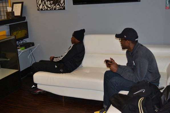 Philip Acheampong and Mike Fofana play some NBA 2K13 while waiting for their turn in the barber’s chair.
