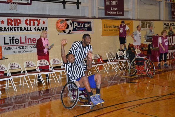 Referee Brandon Bentley shoots a one-handed three sitting down, but decided against adding a blindfold to the mix.
