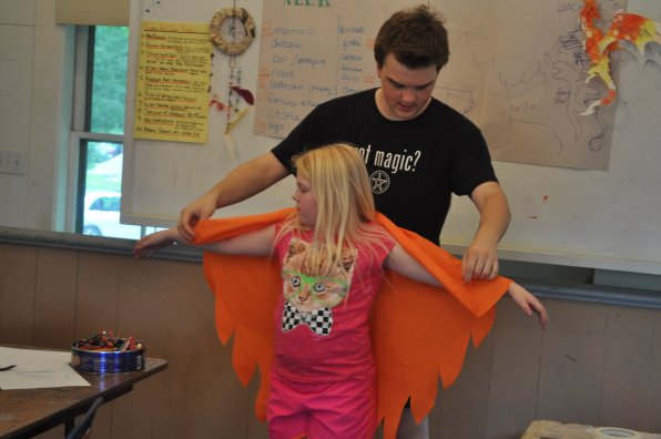 Kimball-Jenkins art camp counselor Owen Geary helps fit Brooke Holmes, 9, with the wings for her phoenix costume as part of fantasy week – as if her T-shirt of a cat in sweet hipster glasses wasn’t a cool enough costume already.