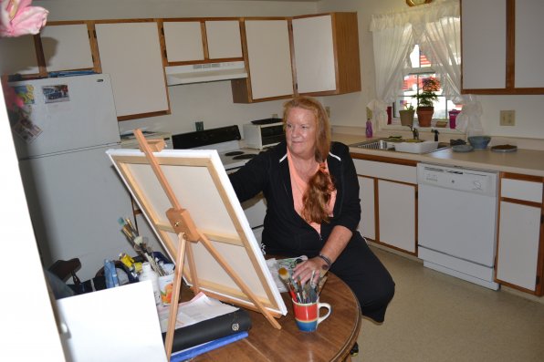 Robin Sanford Lamson works on a painting at her kitchen table.