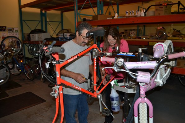 Volunteer Curt Crow and Recycled Cycles employee Dorrie Wallace work their magic to fix a bike.
