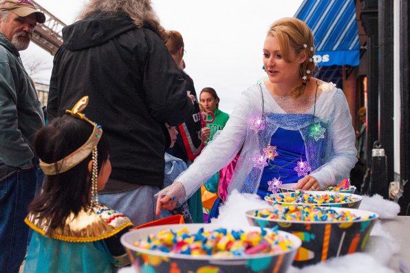 Justine Hayward, a co-owner of Trilogy Hair Studio, passes out candy to trick-or-treaters while dressed as Elsa from “Frozen.”