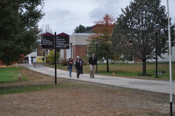 Tori Ghanem, Josh Jacob and Devon Greer cruise through campus at NHTI on Friday afternoon in the shadow of signs directing them to several places where higher education happens or places where food is served to people between quests for higher education.