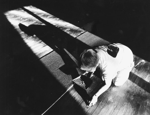 Joyce Olson scrapes gum off the floor after seats were moved so the floor could be refurbished.