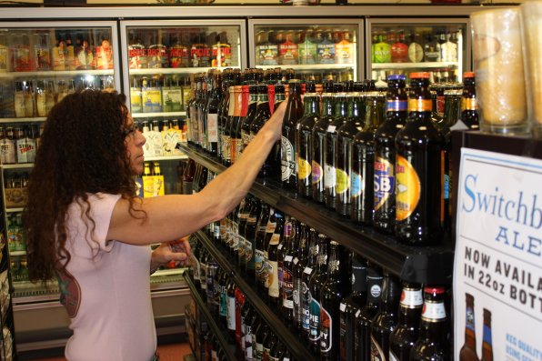 Owner Barb Lambert stocks a shelf with 22-ounce bottles.