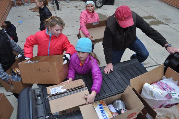 Joe Larochelle (right) climbs into the back of a pickup truck to help Morgane Orcutt, Mary Martinson and Colette Brochu load a few of the boxes collected during the recent Christa McAuliffe School food drive.  How much food was there? Enough to fill three cars and an aircraft carrier! Or at least three cars.