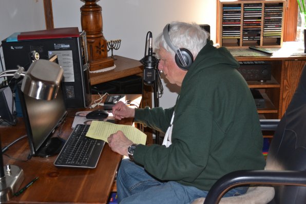 Frank Wilner looks over the script for one of his upcoming shows in his home studio.