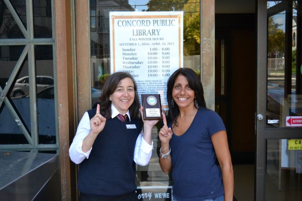 Deb Baker, adult services manager at Concord Library, and Joann Salemy, administrative specialist, let everyone know who took home the championship plaque in its library card challenge with Hooksett.