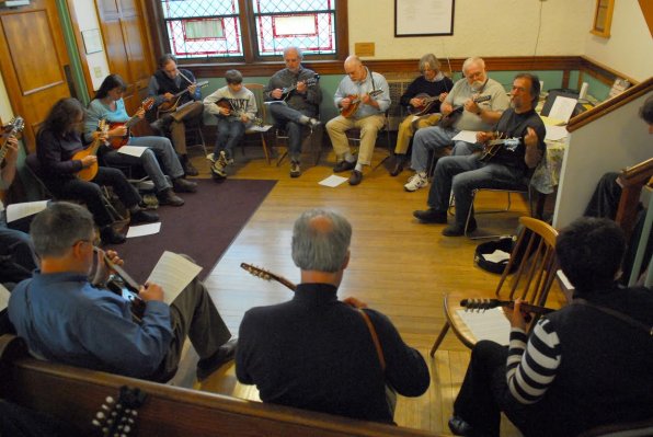 A group of tiny-stringed-instrument enthusiasts play.