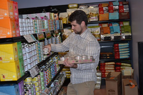 Burr-Mecum patiently stocks cans of cat food.