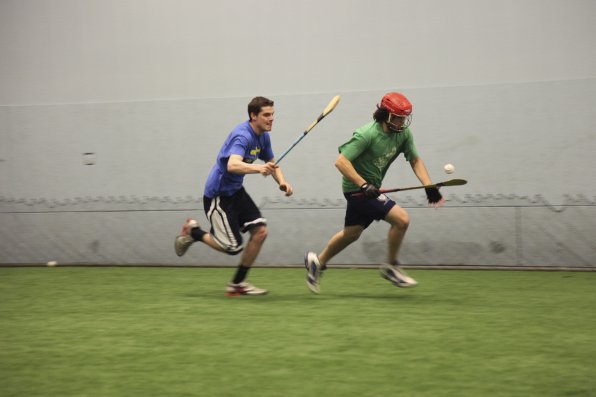 From left: Matt Polhemus chases after Will Mullen while attempting to smack the sliotar off Mullen’s hurley.
