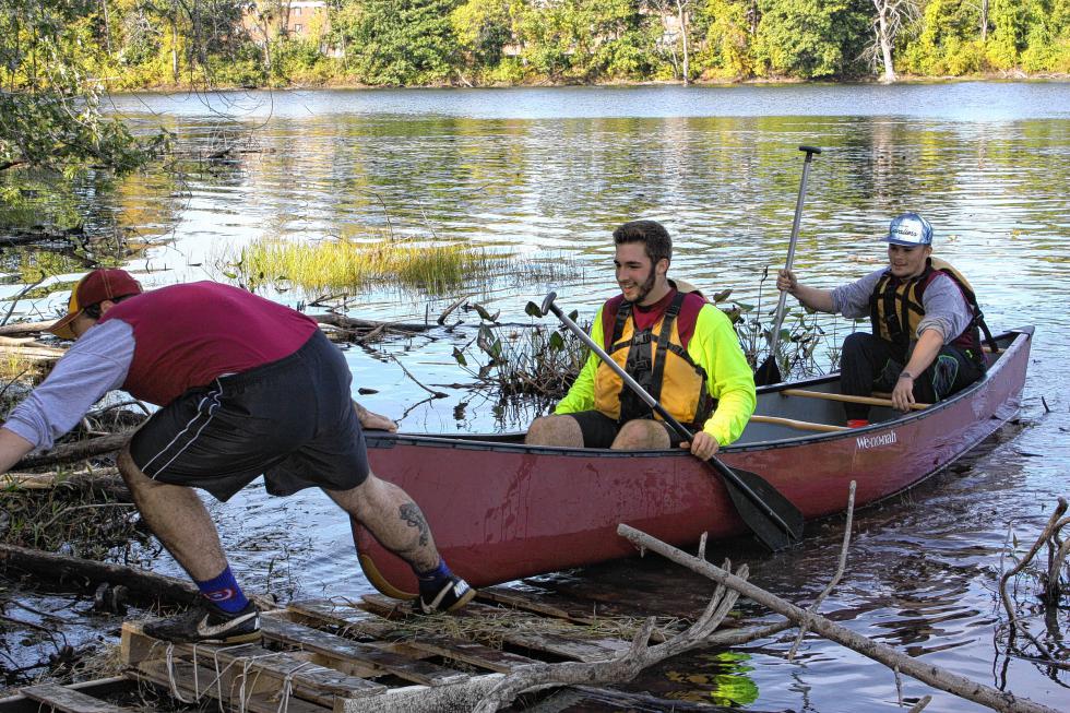 NHTI Strout Hall team members Jacob Hinton, Kyle Deluca and Jared Stephenson prepare to canoe out of the water and back up to the course at NHTI's Qunoquer the Quad. (JON BODELL / Insider staff) - 
