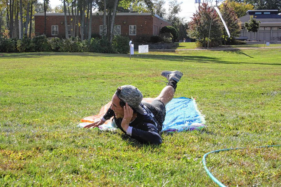 Kieran O'Brien, an RA at Strout Hall at NHTI, styles it as he slip-n-slides across the finish line at the third annual Quonquer the Quad event at the NHTI campus in Concord on Sunday. (JON BODELL / Insider staff) - 
