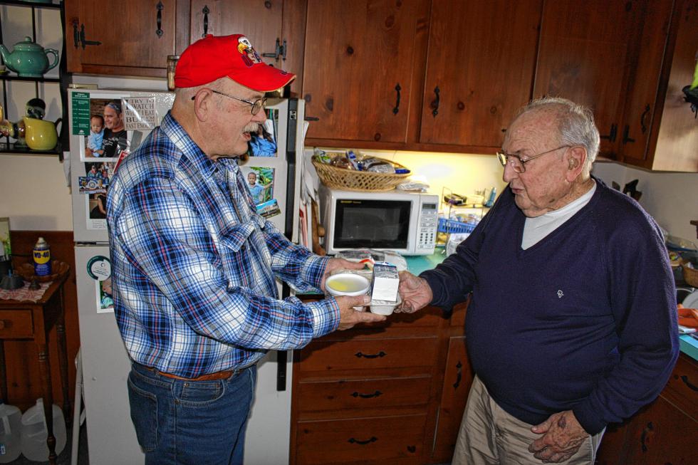 Steve Indyk hands a meal over to George Descoteau at Descoteau’s home in Bow last week. (JON BODELL / Insider staff) -