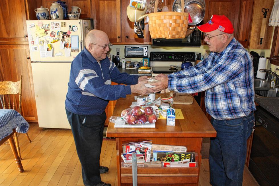 Steve Indyk (right) makes the hand-off to Norman Rhodes Sr. in Bow. Both men with both hands on the package, for maximum meal security. (JON BODELL / Insider staff) -