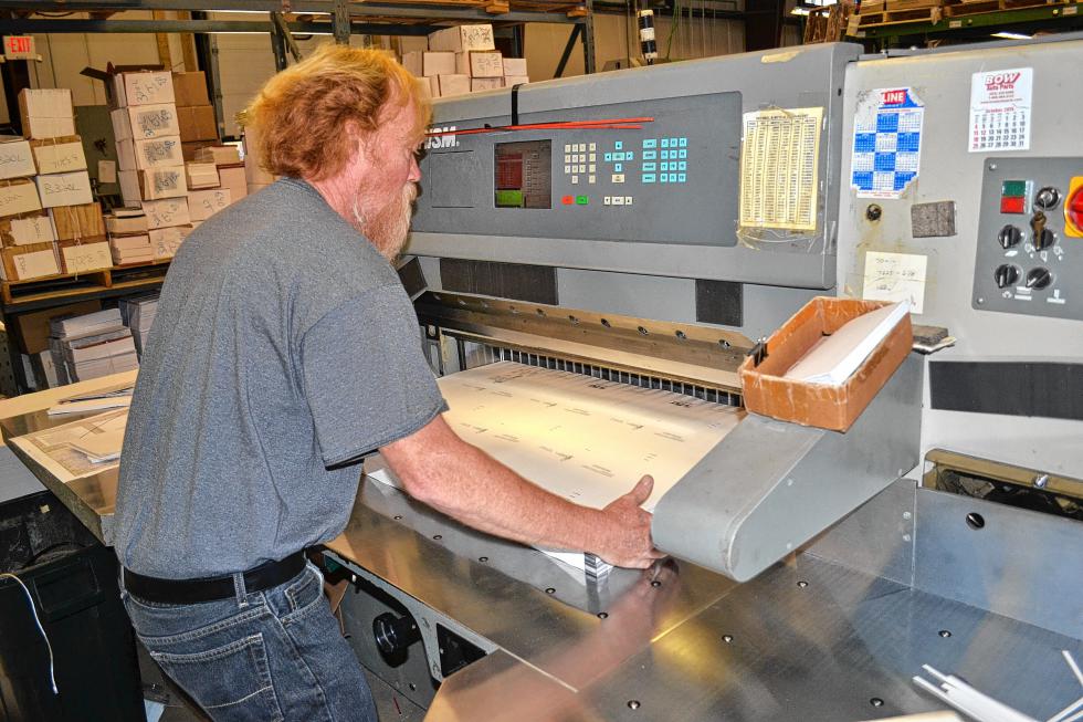 Herb Sherman puts a sheet of signatures (that’s fancy book lingo for pages) into the guillotine cutter. (TIM GOODWIN / Insider staff) -