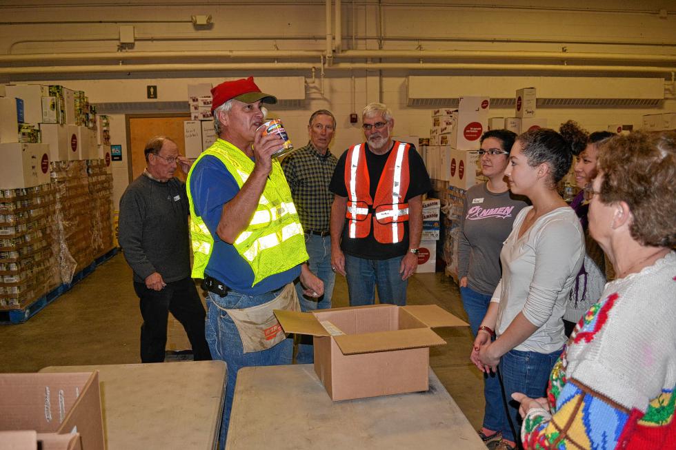Floor supervisor Lee Lajoie does a little show and tell to make sure the volunteers put the canned goods in the right spot in the box. (TIM GOODWIN / Insider staff) - 
