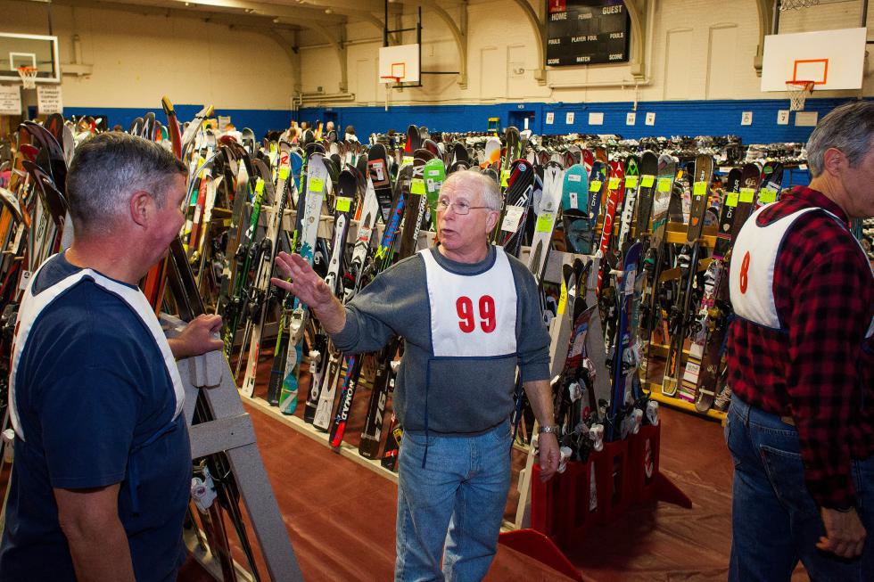 Bill Mitchell (center) directs volunteers during set up for the annual Ski and Skate Sale at the Green Street Community Center in Concord, Thursday, Dec. 4, 2014.  (ELIZABETH FRANTZ / Monitor staff) - ELIZABETH FRANTZ | Concord Monitor
