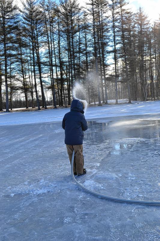 Patrick Lanman uses a fire hose to spray down the pond at Beaver Meadow Golf Course last week. The city’s parks and recreation staff does it just about every day to provide a good skating surface. (TIM GOODWIN / Insider staff) -