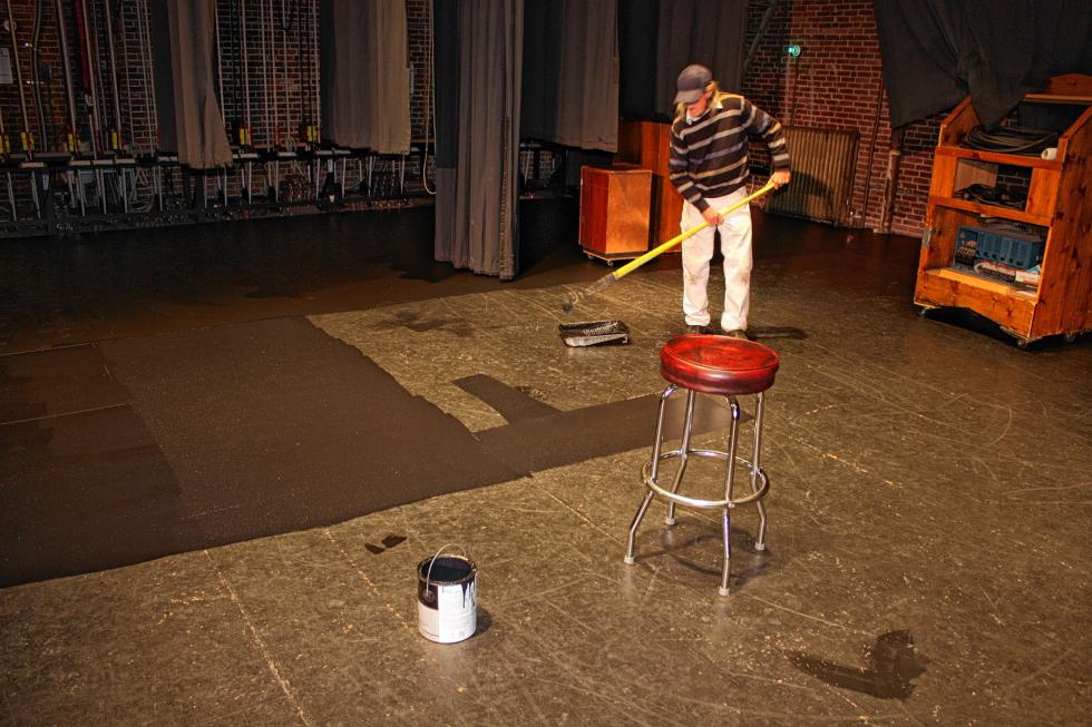 Rudy Douville rolls a fresh coat of black paint onto the stage floor at the Audi. (JON BODELL / Insider staff) -