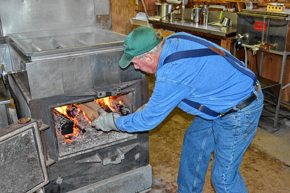 Dean Wilber adds a log to the fire to keep the temperature up while boiling last week. (TIM GOODWIN / Insider staff) -