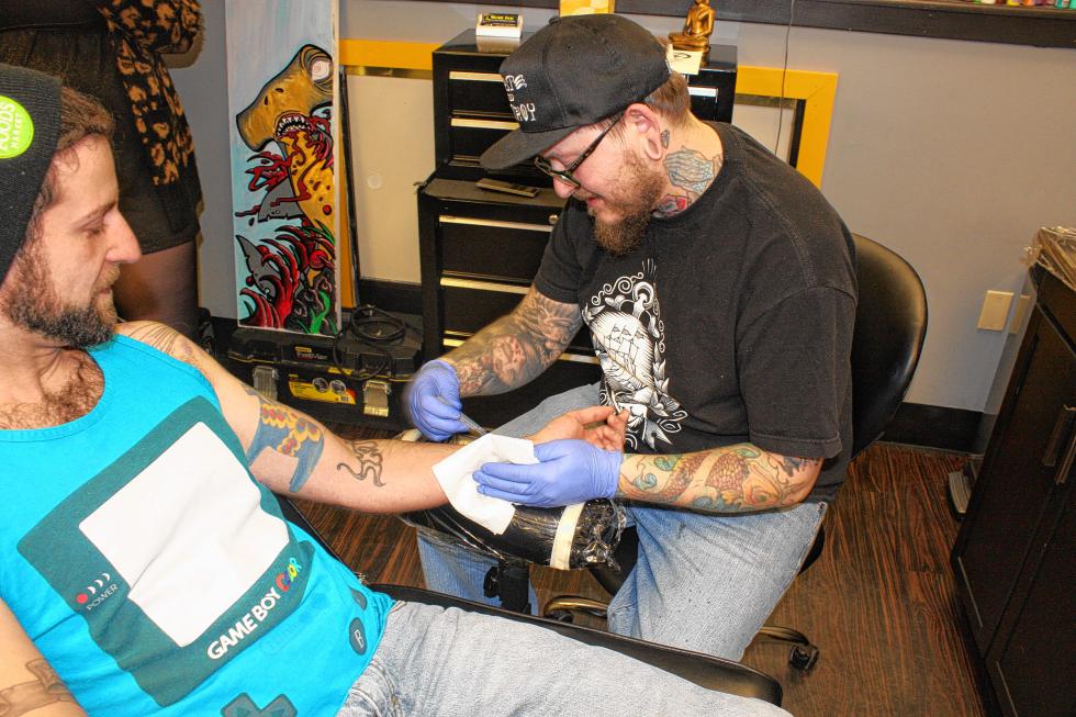 Tattoo artist Russ Collins shaves Joel Ste. Croix's arm before putting some ink on it. A good tattoo artist always shaves the area about to be tattooed to make sure there's a smooth surface. (JON BODELL / Insider staff) -