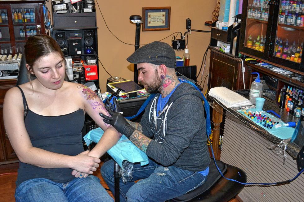 Sean Ambrose, owner of Arrows & Embers Tattoo, works on the arm of Ashley Johnson last week at his Pleasant Street Extension shop. (TIM GOODWIN / Insider staff) -