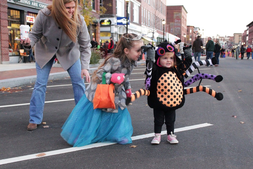 SUSAN DOUCETPaisley Callanan, 19 months, raises her arms to show off her spider costume with a little encouragement from her sister Lucy, 4, and her mom, Kelly, in downtown Concord on Friday, Oct. 30, 2015. The girls' father, Philip Callanan, is principal of Mill Brook School. Halloween Howl, an Intown Concord event, was held Friday. Children, pets and families in costumes trick or treated downtown, danced and participated in a costume parade.(SUSAN DOUCET / Monitor staff)