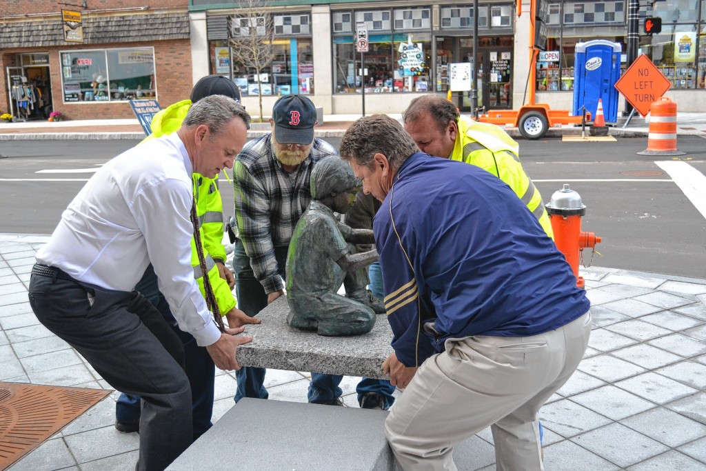 Tim Goodwin / Insider staffA bronze boy holding a turtle is the first piece of public art installed under a new initiative. Created by Beverly Benson Seamans, the piece titled “A Moment in Time” sits on a granite squares near the corner of South Main and Pleasant streets. Top left: An up-close look at Concord’s new outdoor art. Above: City Manager Tom Aspell and members of General Services help move the 300-plus pound statue. There’s no job too small for our city manager. Bottom left: Seamans’s son, John, and grandson, Daniel, guide it onto the South Main Street sidewalk.