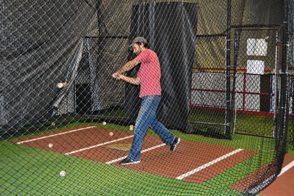 Top: Not the best form we’ve seen, but Jon still fielded the ball cleanly. Bottom: Jon puts a good swing on one – after about a dozen whiffs – in the batting cage. The 70 mph setting was his sweet spot.