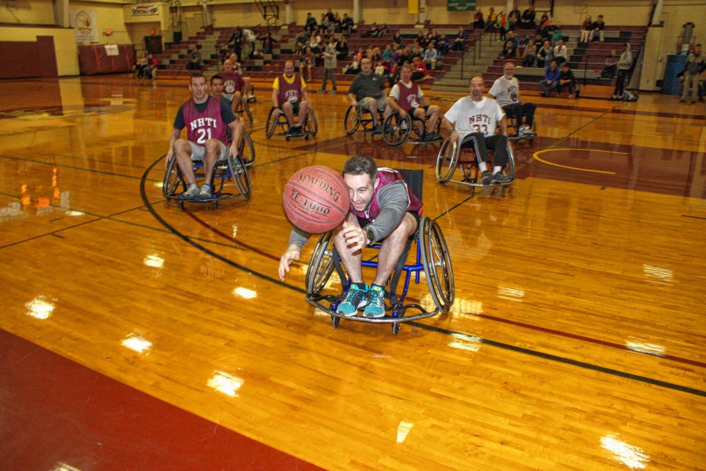 Tom Warner of the NHTI admissions department wheels toward a loose ball during the Wheelchair Basketball Benefit at NHTI last week. (JON BODELL / Insider staff)