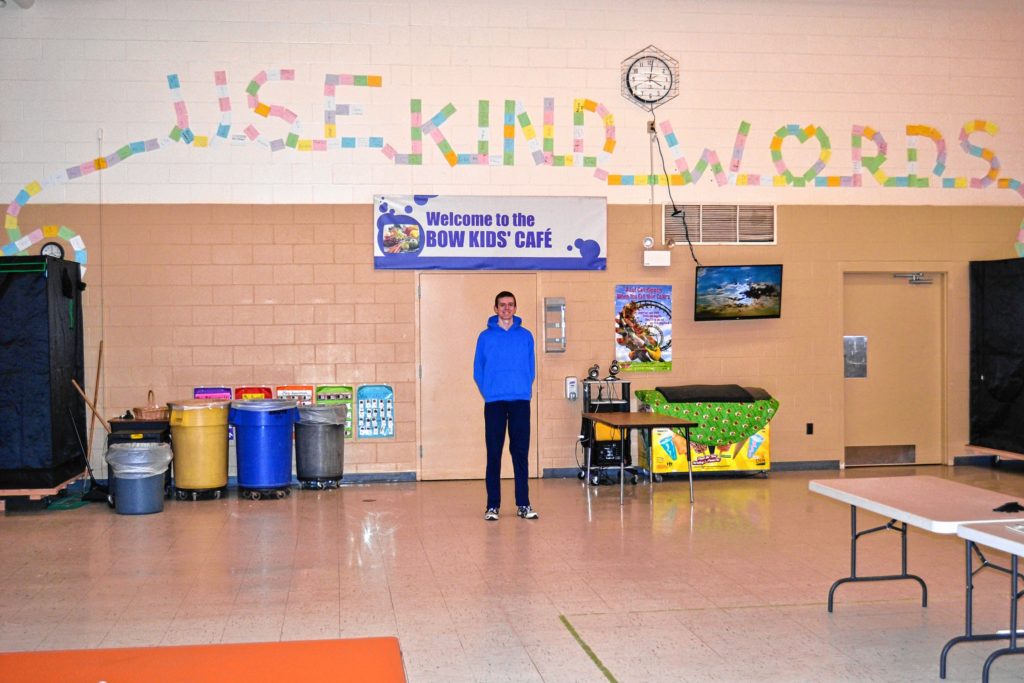 Bow High senior Jack Rich poses with the kindness caterpillar at Bow Elementary that was created through positive notes following Rich's senior project to bring in a friendship bench.