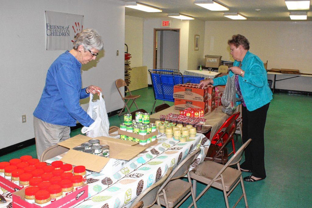 Fran Philippe (left) and Kathy Bush, RSVP volunteers with The Friends Program, fill bags of food at Friends of Forgotten Children last week. Every week,  volunteers work to fill 28 bags of food to be distributed to Penacook  Elementary School students in need.