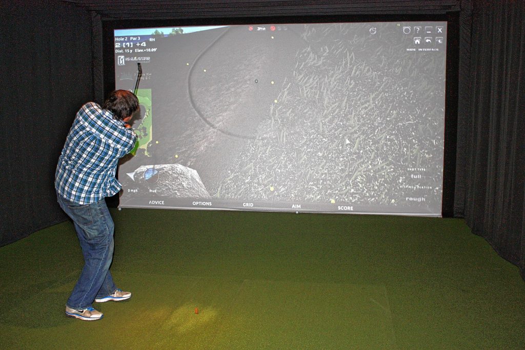 Tim does his best to chip his ball out of the worst terrain imaginable at Beaver Meadow Golf Course’s new indoor golf simulator. Once you’re out of the ditch, it’s pretty fun. See what we mean on page 6.       
