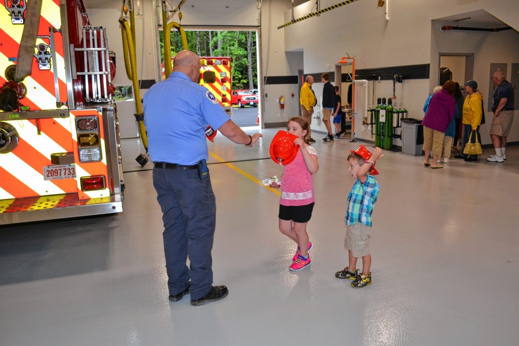 Alana Bridges, 8, and Aidan Bridges, 4, receive honorary Bow Fire Department helmets from Lt. Tom Ferguson during the Bow Safety Center open house. TIM GOODWIN / Insider staff