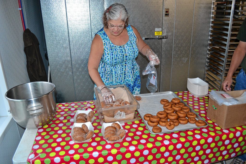 Lin Moulton rolls the apple cider doughnuts in the cinnamon and sugar mixture at Carter Hill Orchard. TIM GOODWIN / Insider staff