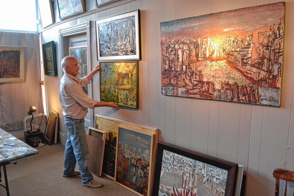 Dave Wiggins adjusts one of his works hanging in the studio he shares with longtime friend Doug Prescott at 3 Pleasant St. Wiggins and Prescott are having a two-night-only reception this Friday and Saturday. TIM GOODWIN / Insider staff